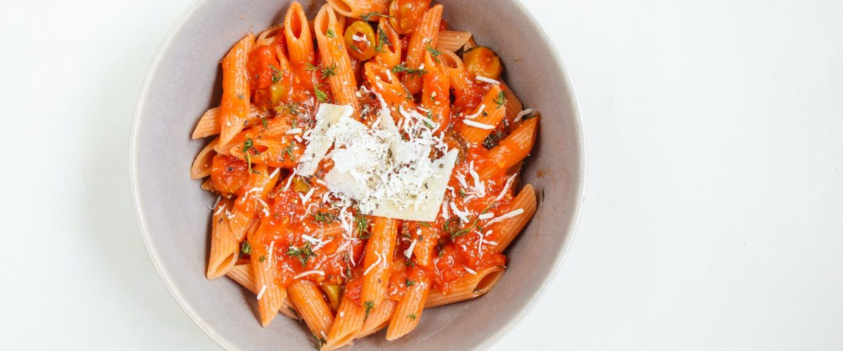 a bowl of delicious penne pasta topped with grated cheese